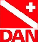 Logo rouge et blanc de DAN avec bande diagonale blanche et croix, texte "DAN", mention Nusa Penida non visible mais relié à la plongée.