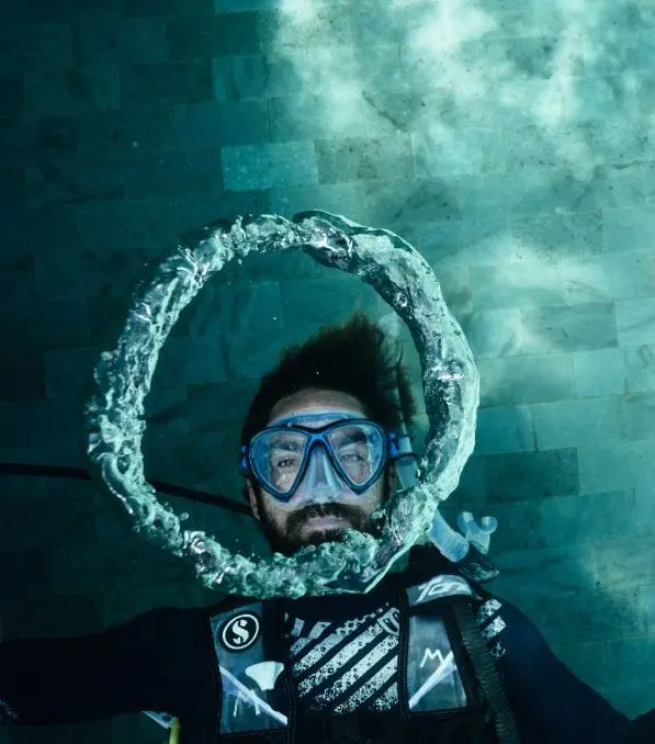 Plongeur à Nusa Penida formant un anneau de bulles autour de son visage avec masque et détendeur sous l'eau.