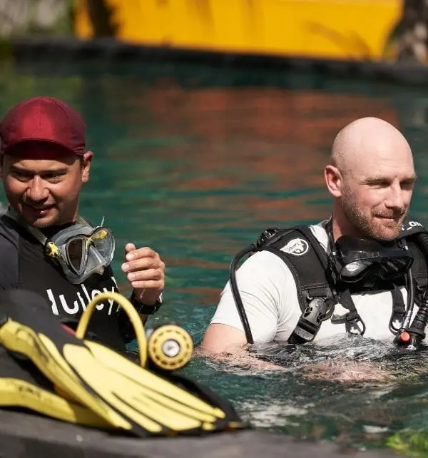 Deux plongeurs en tenue de plongée préparant leur équipement à l'eau près d'une embarcation, Nusa Penida.