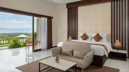 Chambre d'hôtel spacieuse à Nusa Penida avec lit king, canapé et baie vitrée ouverte donnant sur terrasse et vue sur la mer.